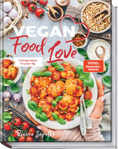 Cover des Kochbuches "Vegan Food Love" von Bianca Zapatka: Ein Teller voller herzförmiger Ravioli gehalten von zwei Händen. Drum herum sind verschiedene Lebensmittel wie Tomaten oder Zwiebeln arrangiert.